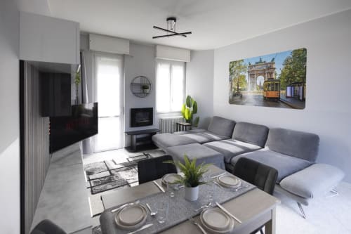 Modern Milano apartment living room with gray sectional sofa, dining table, wall-mounted TV, and city views
