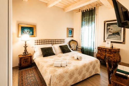 Elegante camera da letto presso Al Battistero Luxury Suite a Ravenna con letto matrimoniale, vista sulla città, travi in legno e arredamento classico