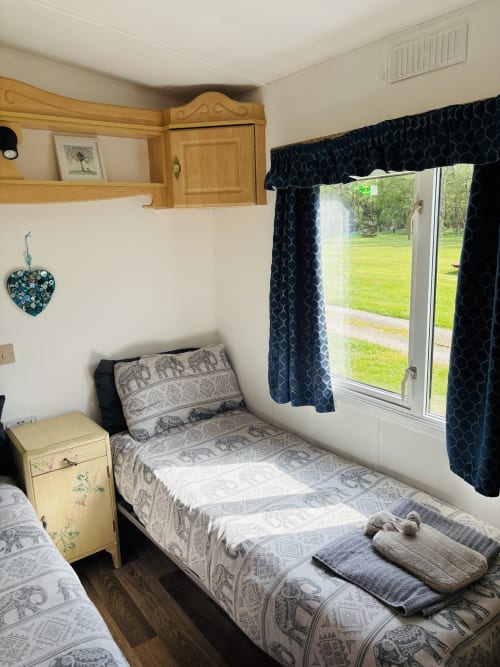 Cozy bedroom in Owl Country Cabin at Postwood Gardens Campsite with elephant print bedding, garden views, and dark patterned