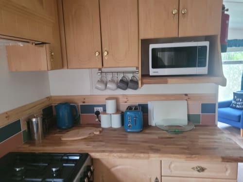 Kitchen counter in Owl Country Cabin at Postwood Gardens Campsite with microwave, kettle, and cooking appliances