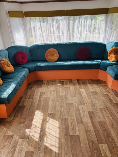 Teal sectional sofa with colorful round pillows in the spacious lounge area of Fox Country Cabin at Postwood Gardens Campsite