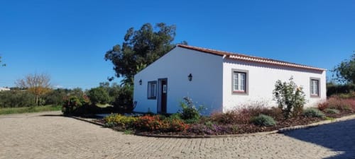 Casarão branco com acabamento em telha de barro em Monte da Morena Agro Turismo em Serpa, Portugal, cercado por jardins paisagísticos