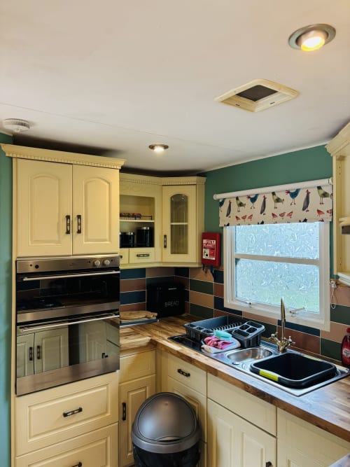 Cream kitchen with green walls, stainless steel appliances, and wooden countertops in Deer Country Cabin at Postwood Gardens