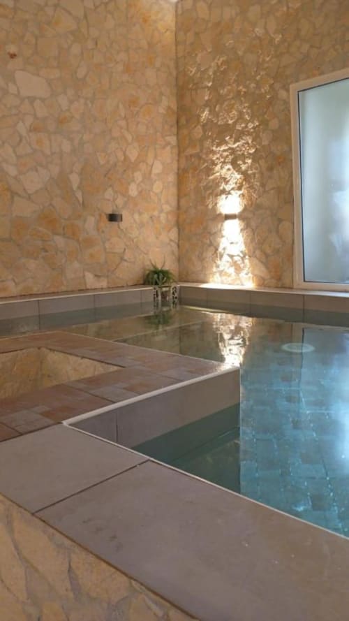 Modern spa pool at Neapolis Tecnotourist with marble walls, natural light, and tranquil water feature