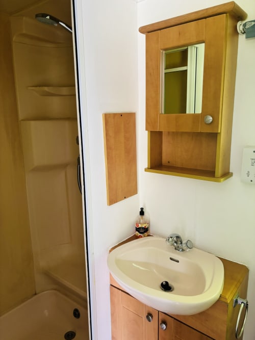Bathroom in Fox Country Cabin at Postwood Gardens Campsite with round sink, wooden vanity, and mirrored medicine cabinet