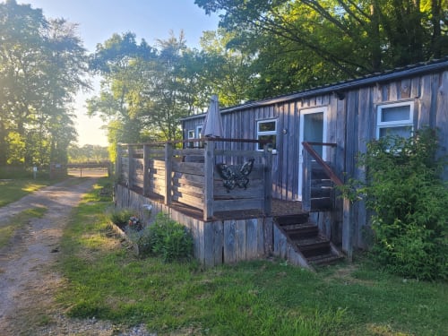 Rustic wooden cabin at Postwood Gardens Campsite in Kentisbeare with decked porch, windows, and garden views surrounded by