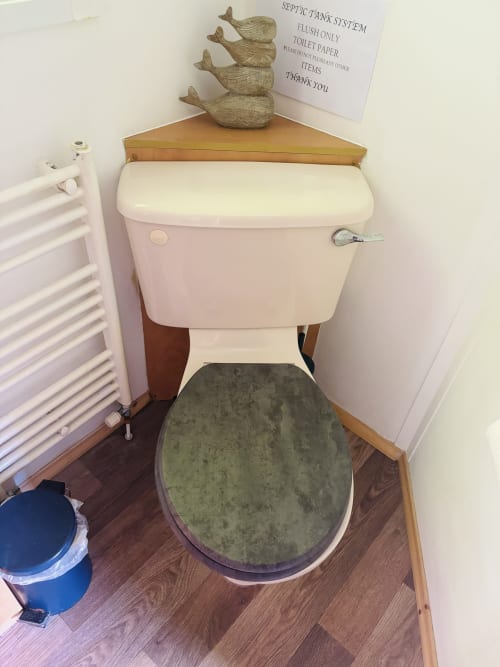 Toilet with green seat at Postwood Gardens Campsite in Kentisbeare, septic tank system signage visible above