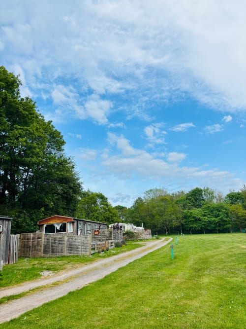 Postwood Gardens Campsite caravans with green fields and trees under blue sky in Kentisbeare