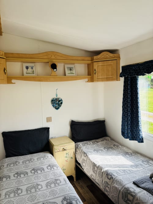Cozy twin bedroom in caravan at Postwood Gardens Campsite, Kentisbeare with wooden furnishings