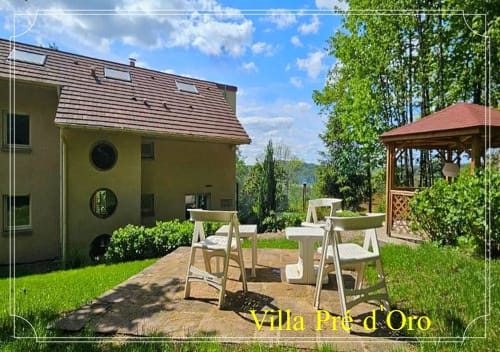 Jardin de la Villa Pré d'Oro avec coin détente, maison jaune et vue sur les montagnes à Amage