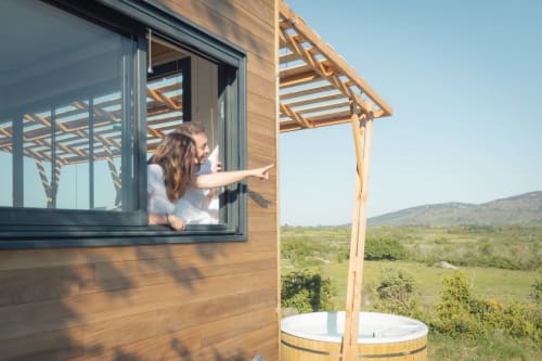 Femme à la fenêtre en bois avec vue sur la vallée à Pépite BnB à Villeneuve, France, avec bain à remous et pergola
