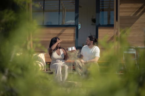 Couple savourant des verres en terrasse à la guest-house Pépiite à Villeneuve, entouré de verdure