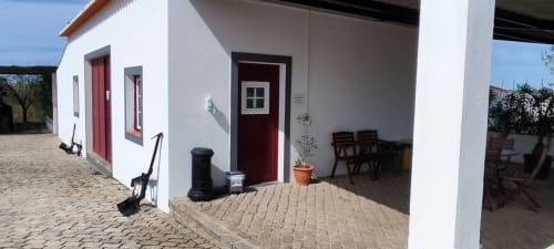 White rural cottage with red doors at Monte da Morena Agro Turismo in Serpa, Portugal, featuring brick patio and covered