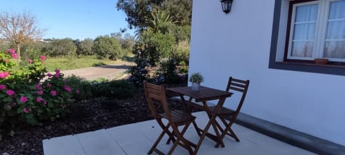 Patio seating at Monte da Morena Agro Turismo with wooden chairs, pink flowers, and rural Serpa countryside views