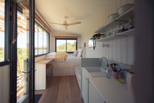 Modern tiny home interior with kitchenette, bed with mountain views, and large windows at Pépiite Gorges de l'Ardèche, France