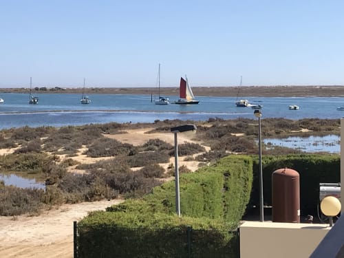 Barcos à vela ancorados em águas azuis perto de Tavira, Portugal, com praias arenosas e marismas do Rio vistos do apartamento River House