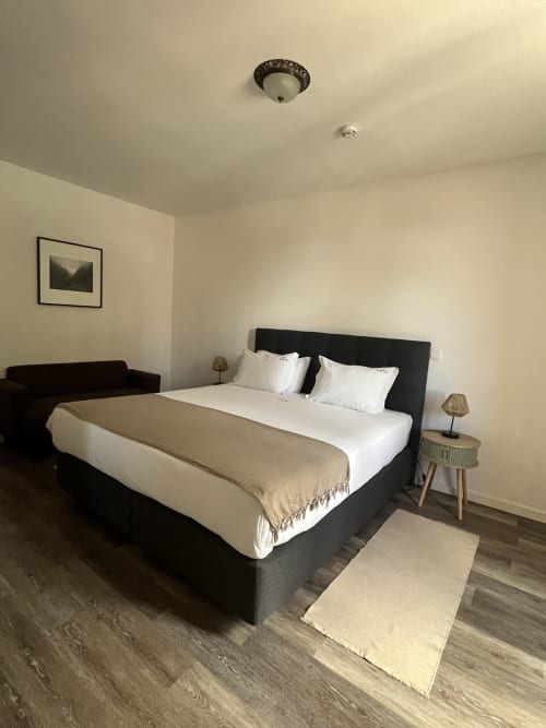 Quarto moderno no Rum Inn na Madeira com cama queen, cabeceira preta, roupa de cama branca e decoração minimalista