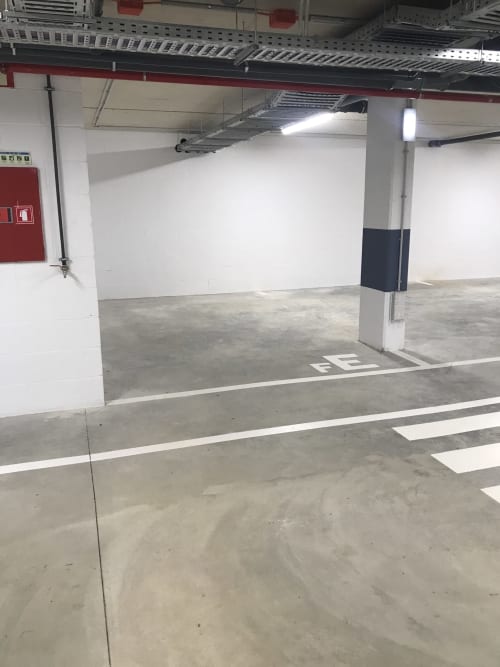 Garagem de estacionamento subterrânea vazia no Break Lovers apartment em Tavira com piso de concreto e marcações de parede brancas