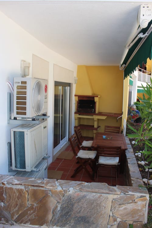 Aconchegante sala de jantar da Seahorse House em Tavira com mesa de madeira, parede de destaque em amarelo e unidade de ar condicionado moderna