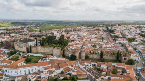 Aerial view of Serpa's historic walled town with terracotta roofs, castle ruins, and surrounding countryside in Portugal