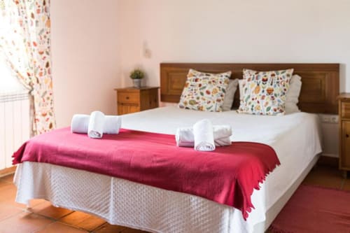 Bright Superior Double Room at Monte Da Morena with white bed, red blanket, colorful pillows, wooden headboard, and