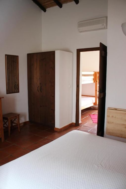 Spacious Superior Double Room at Monte Da Morena with dark wood wardrobes, terracotta floors, and access to garden terrace.