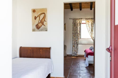Superior double room with wooden bed frame at Monte Da Morena Agro-Turismo in Serpa, Portugal, showing terracotta floors and