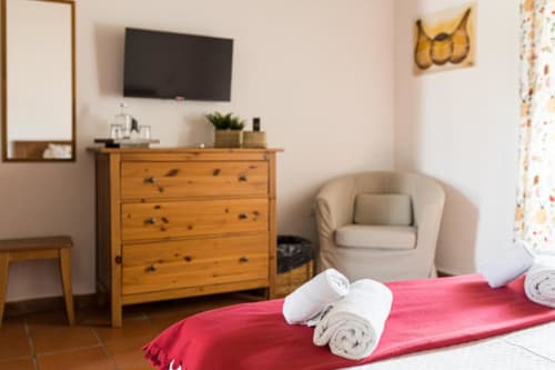 Superior Double Room at Monte Da Morena, Serpa with red bedding, rolled towels, wooden dresser, beige armchair, and
