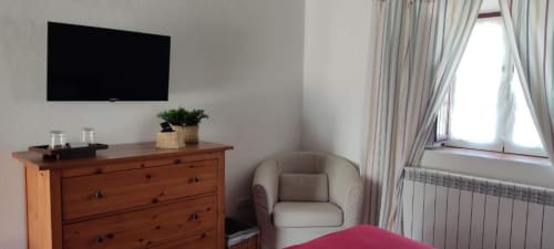 Standard double room at Monte Da Morena with flat-screen TV, wooden chest, beige armchair, and garden views through striped