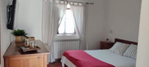 Bright bedroom at Monte Da Morena with double bed, wooden desk, potted plant, window with garden views, and striped pillows