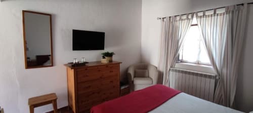 Standard double bedroom at Monte Da Morena Agro-Turismo in Serpa with wooden dresser, TV, mirror, and garden view