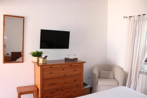 Standard Double Room with wooden dresser, wall-mounted TV, mirror, armchair, and garden view curtains at Monte Da Morena