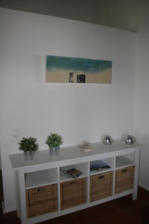 Modern white storage unit with woven baskets, potted plants, and decorative spheres in Monte Da Morena apartment, Serpa