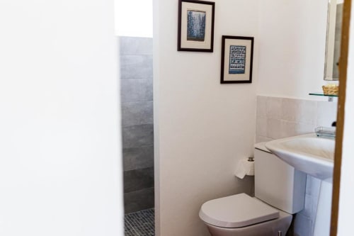 Modern bathroom with toilet, sink, tiled shower, and framed artwork at Monte Da Morena Agro-Turismo in Serpa, Portugal