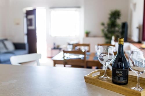 Wine bottle and glasses on wooden table in bright apartment dining area at Monte Da Morena, Serpa