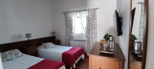 Twin bedroom at Monte Da Morena with floral curtains, red throws, wooden furniture, flat-screen TV, and garden views in Serpa