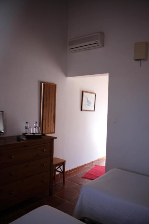 Spacious bedroom at Monte Da Morena Agro-Turismo with wooden dresser, twin beds, air conditioning, and garden view access in