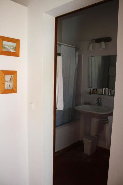 Bathroom with sink, mirror, toilet, shower curtain, and towel rack at Monte Da Morena in Serpa