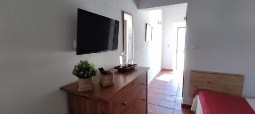 Modern bedroom at Monte Da Morena with flat-screen TV, wooden dresser, and access to terrace in Serpa, Portugal