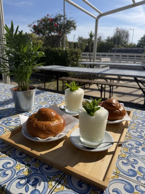 Terrazza esterna di Baia Dorica con pasticcini, cocktail alla menta, piante in vaso e vista sulla campagna sotto pergolato