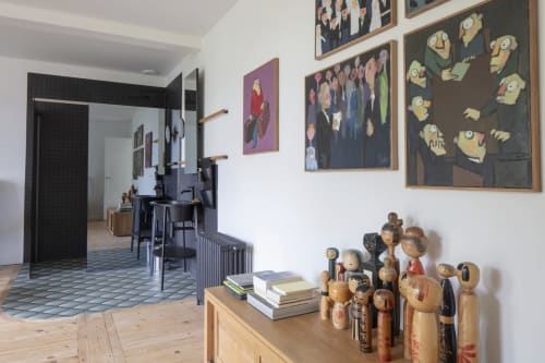 Chambre d'hôte de la Villa Sonneville à Roubaix, mobilier en bois, œuvres encadrées et vue sur le jardin par la porte ouverte