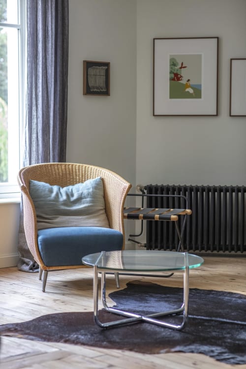 Fauteuil en rotin moderne avec coussin bleu et table en verre dans le salon du jardin de la Villa Sonneville, Roubaix