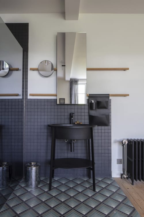 Salle de bain moderne à la Villa Sonneville avec vasque noire sur piédestal, murs carrelés, étagères en bois et miroir rond à Roubaix