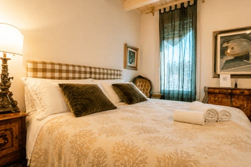 Elegante camera da letto presso Al Battistero Luxury Suite a Ravenna con testiera scacchiera, cuscini verdi e vista sulla città