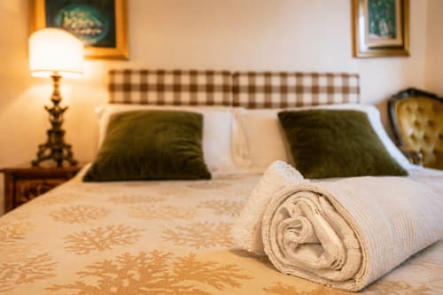 Camera elegante della Al Battistero Luxury Suite a Ravenna con asciugamani arrotolati, cuscini verdi e vista sulla città