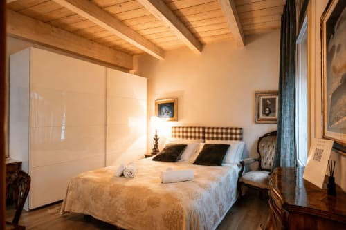 Lussuosa camera da letto all'Al Battistero con travi in legno, testata a quadri, vista sulla città e arredi eleganti a Ravenna