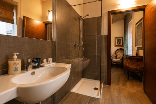 Bagno moderno di Al Battistero Luxury Suite a Ravenna con doccia walk-in, lavabo bianco e dettagli in legno