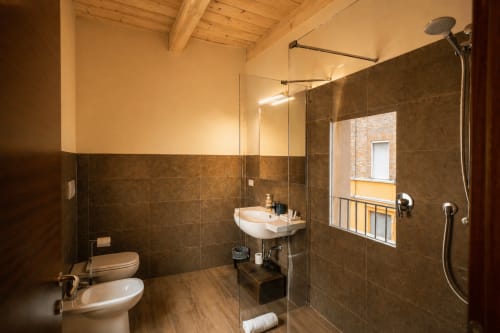 Bagno moderno presso Al Battistero Luxury Suite a Ravenna con piastrelle scure, doccia a pioggia e vista sulla città
