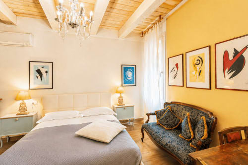 Camera da letto lussuosa al Battistero di Ravenna con pareti gialle, travi in legno, arredi eleganti e comfort moderni