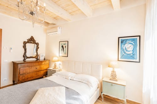 Camera elegante ad Al Battistero a Ravenna con letto bianco, mobili in legno, travi a vista e vista sul giardino